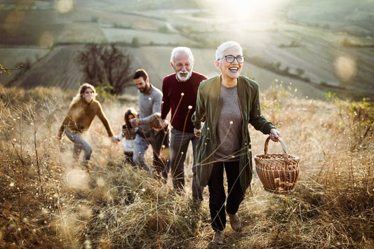 Happy senior woman leading her family to a perfect picnic place on the hill.