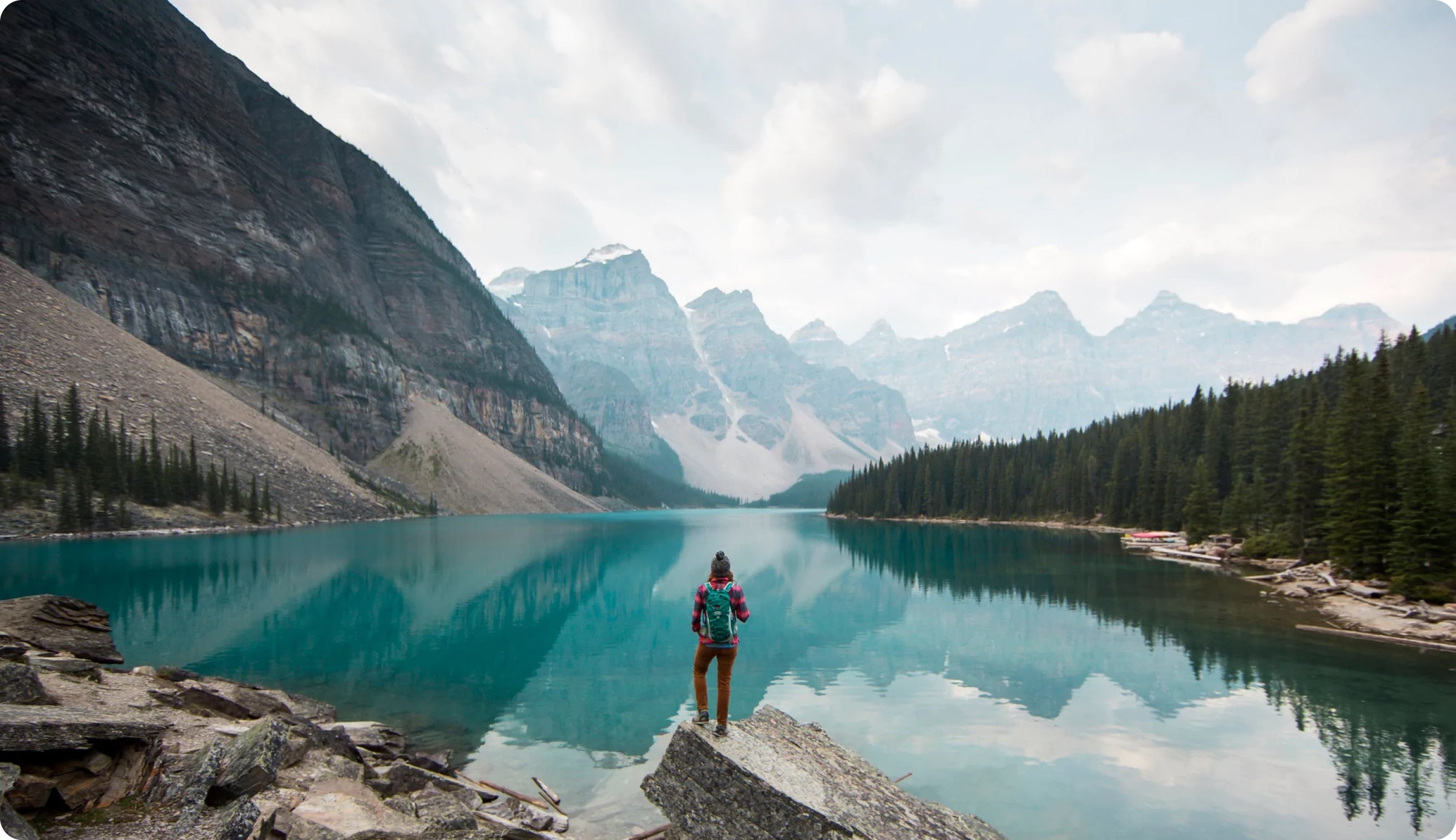 High mountains reflect on a placid blue lake surrounded by lush evergreens 