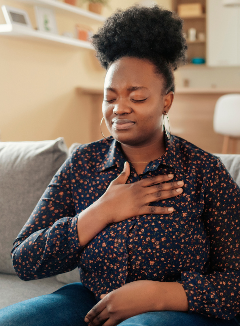 Woman sitting down with her hand on chest